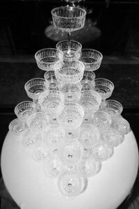 Luxury champagne tower with vintage coupe glasses on a white linen table at a wedding party.