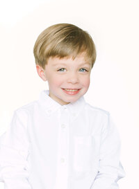 Young boy smiles for camera during an heirloom portrait session with Morgan Leigh Photography.