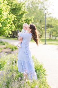 Mother kissing her baby boy in a bright spring field with purple flowers outside the Nashville Parthenon