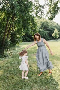 Mom twirling young daughter during a fun and candid moment while taking family photos in Etobicoke.