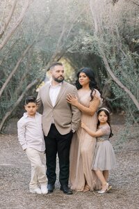 The Dilorio family with their children posing together in a scenic outdoor setting in Las Vegas, featuring a stylish and elegant family portrait surrounded by natural greenery.