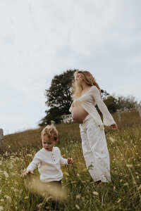 pregnant mother dancing in a field with her toddler.