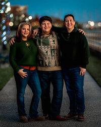 Parents standing with their teenage son during a downtown New Bern family photography session at night