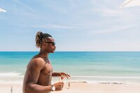 Traveler enjoying a drink on a white sand beach with turquoise waters, perfect for a tropical escape.