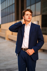 Senior portrait in downtown Mobile, Alabama— holding his suit jacket and looking off to the side.