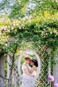 Image through a round opening of two brides about to kiss.