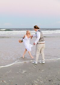 Professional photography by Nature's Child Photography: St. Augustine, wedding capturing a bride laughing as she runs barefoot through the surf toward her groom, waves curling around their feet.