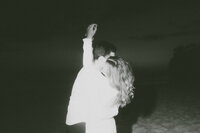 black and white image of couple embracing on beach, cinematic wedding portait