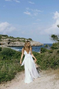 Elegant bride posing on the Mediterranean coast of Mallorca during golden hour, featuring a stunning bridal look and scenic sea background.