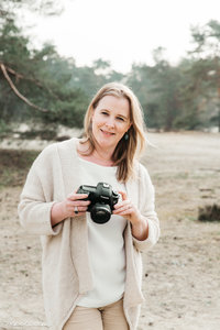 Zakelijk portret in de duinen van Utrecht met camera in haar handen