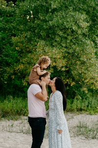 parents kissing with child on beach