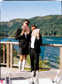35mm film photo of a gay couple holding fans at a wedding ceremony at West Coast Wilderness Lodge