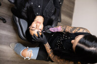 Professional beauty artist leaning over client during brow procedure. Photograph by Yucaipa branding photographer Kaitlyn Dawn Photography.