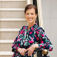 Jessica wearing a white blazer, smiling as she writes in her planner