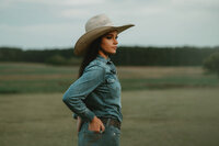 Senior portrait at Triple T Farms in Fruitdale, Alabama — denim outfit and cowboy hat, hands in
back pockets.