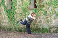 Man lifting his girlfriend while kissing her in front of a brick wall in a park near Pasadena during an engagement photo session.
