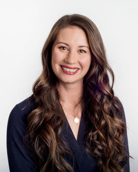 Headshot-of-woman-with-long-curly-hair-and-navy-shirt