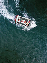 A dynamic aerial shot of a couple on a speedboat, capturing a genuine connection and the adventurous spirit of a wedding weekend.