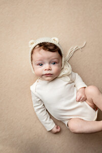 A young baby boy wearing a neutral bear bonnet during his Milestone session in Minnesota.