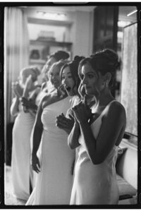Bridesmaids reacting to the bride in her wedding dress. Shot on black and white film in Dallas Texas.