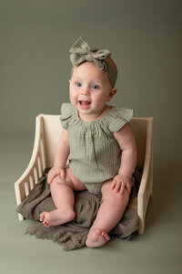 6 month baby girl in a green romper during her milestone session at Jennifer Brandes Photography studio near Nicollet, Minnesota.