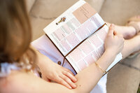 Close-up detail of a high school senior girl holding an open book during a senior portrait session, lifestyle photography by Kaitlyn Dawn Photography