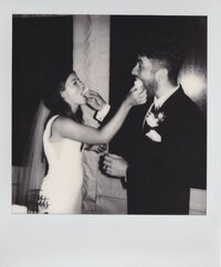 Polaroid snapshot: Newlyweds share a sweet moment, feeding each other cake during their wedding celebration