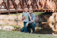 Father crouching beside his young son on a wooden bridge during a Cleveland family photography session