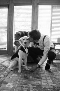 Groom kisses his dog on his wedding day as he gets dressed.
