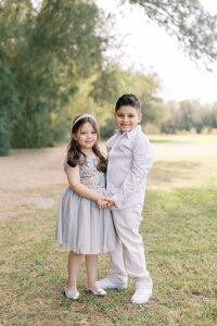 Portrait of the Dilorio family children standing together and holding hands during a bright outdoor photography session in Las Vegas, capturing a sweet sibling moment.