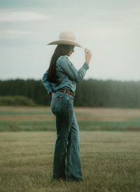 Senior portrait at Triple T Farms in Fruitdale, Alabama — full-body side view, tipping her cowboy
hat