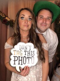 Bride and her friend holding a sign that says Don't Tag this Photo and making funny faces in the camera