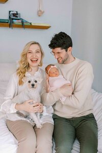 new parents holding their dog and new baby