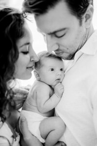 New parents holding newborn together at home Miami newborn photographer