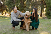 Parents kneeling beside their dog in a grassy park, candid family portrait including pet captured by Kaitlyn Dawn Photography, lifestyle family photographer.