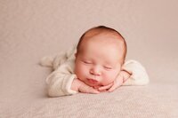 Newborn baby posed in minimalist soft neutral studio portrait