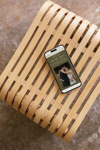 An iphone sits on a wooden chair, displaying a wedding planner's website, designed by Eugene web designer Carrie Bondioli.