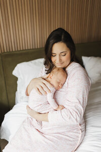 Glowing new mom snuggling her newborn daughter during her lifestyle session captured in her Toronto home.