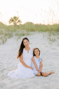 mother and daughter sitting on the beach