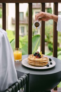 Syrup poured over pancakes and berries during a poolside breakfast