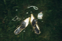Artsy and minimalist flat lay of designer bridal shoes and fine jewelry, captured on film for a documentary wedding story.