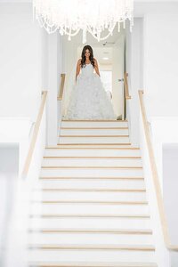 bride coming down stairs at Belle Mer wedding venue