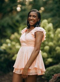 Senior portrait at Bella Sera Gardens in Loxley, Alabama — laughing in a coral dress with
limelight hydrangeas behind her.