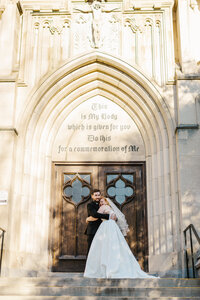 Bride and groom hugging each other outside of ornate church doors