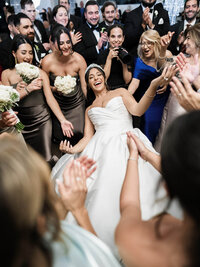 A spirited documentary style wedding photography shot of a bride laughing while dancing, capturing the natural unfolding of the reception.