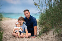 Father walking hand in hand with his two children along a coastal beach path during golden hour family photography session