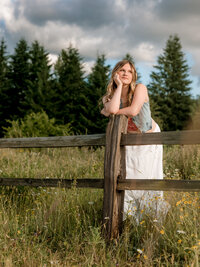 Oregon City high school senior staring in to the sunset leaning against a fence at Powell Butte Nature Park