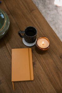 Coffee cup, lit candle, and warm yellow notebook