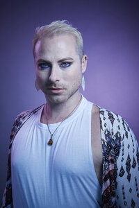 Close-up portrait of Dain August in a white and black patterned outfit, with a confident and intense gaze, photographed by Ylva Erevall.