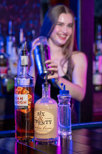 A bartender mixing a drink with the bottles in front of them